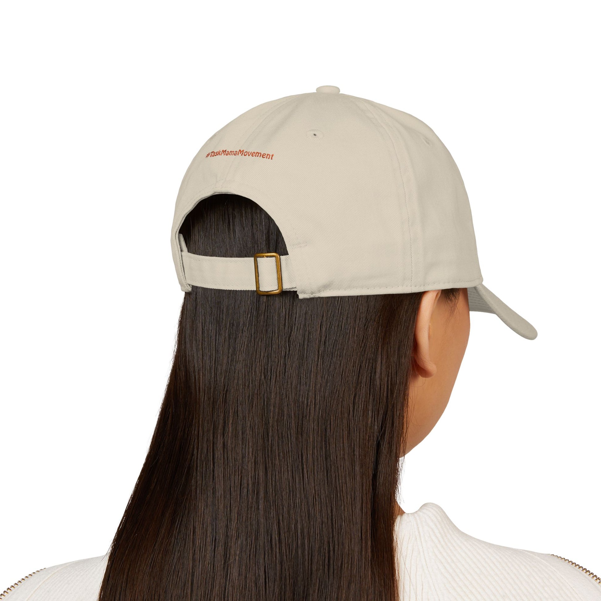 Beige cap worn by a person with long dark hair on a white background