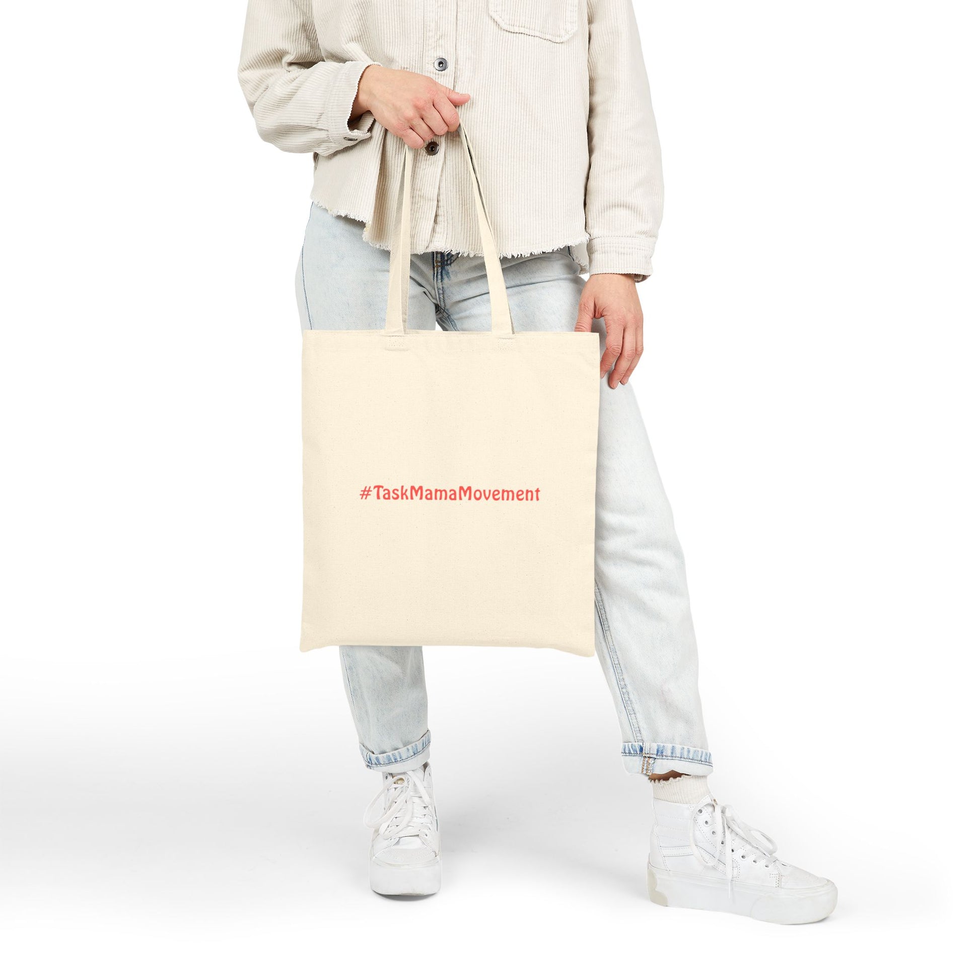 Person holding a beige tote bag with '#TaskMamaMovement' text on a white background